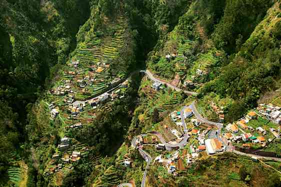 Utsikt over en dal med terrassert jordbruksområder og hus. (AI-generert tekst)