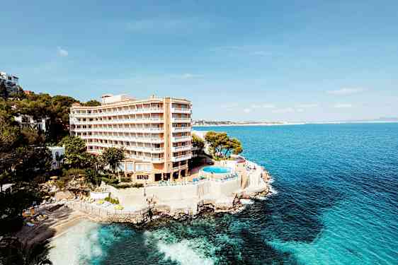 Hotell ved kyst med basseng og utsikt over havet. (AI-generert tekst)