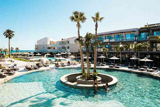 Et utendørs svømmebasseng med omkringliggende solsenger og palmer ved et moderne hotell. (AI-generert tekst)