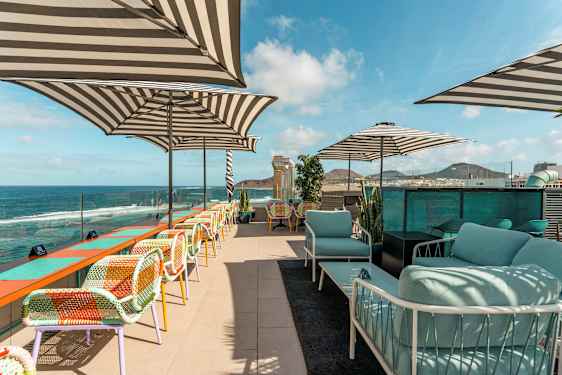 Takterrasse med sitteplasser, parasoller og utsikt over havet. (AI-generert tekst)
