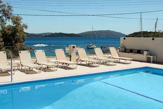 Svømmebasseng med solsenger og havutsikt i bakgrunnen. (AI-generert tekst)