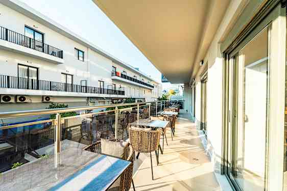 En balkong med bord og stoler, samt utsikt over nabobygninger. (AI-generert tekst)