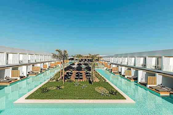 Lang basseng omgitt av moderne hotellkompleks med solsenger. (AI-generert tekst)