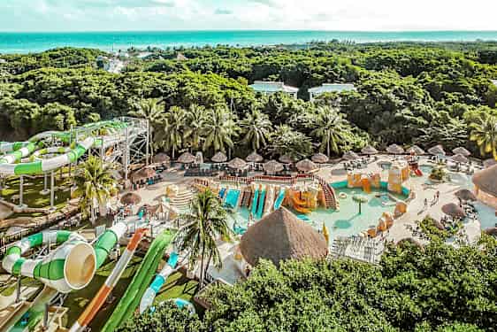 Et bilde av en vannpark med vannsklier, svømmebassenger og grøntområder i bakgrunnen. (AI-generert tekst)