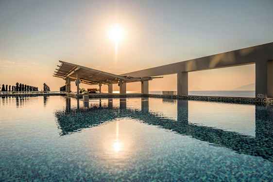 Et svømmebasseng med utsikt over havet og en soloppgang. (AI-generert tekst)