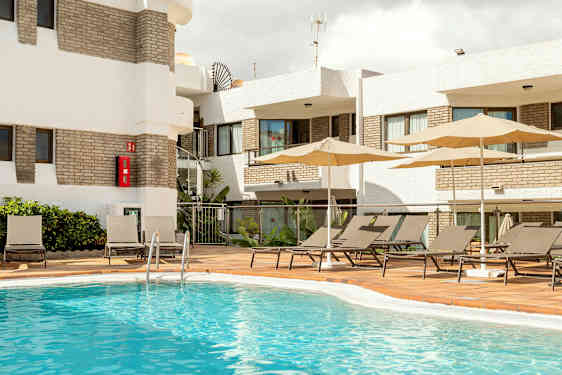 Utendørs bassengområde med solsenger og parasoller ved en bygning. (AI-generert tekst)