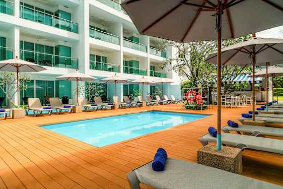 Bassengområde med solsenger, parasoller og en moderne bygning i bakgrunnen. (AI-generert tekst)