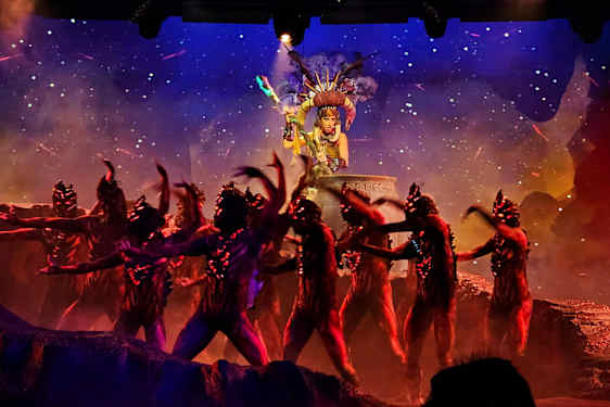 En scenframførelse med dansere kledd i kostymer foran en dekorert bakgrunn. (AI-generert tekst)