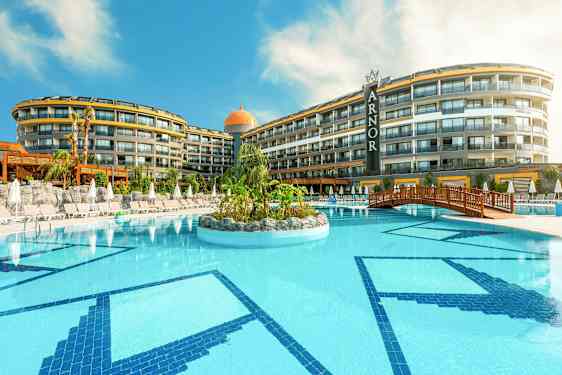 Et hotell med et stort utendørs svømmebasseng, omgitt av solsenger og parasoller. (AI-generert tekst)