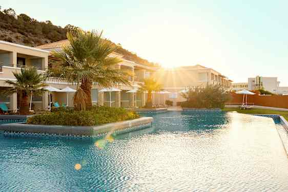 Utendørsbasseng på en resort med palmer i bakgrunnen. (AI-generert tekst)