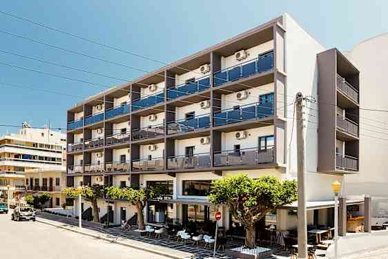 Et fleretasjes hotell med balkonger og uteservering foran, plassert ved en gate. (AI-generert tekst)