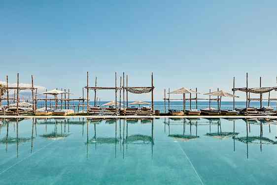 Solstoler og parasoller ved basseng med havutsikt. (AI-generert tekst)