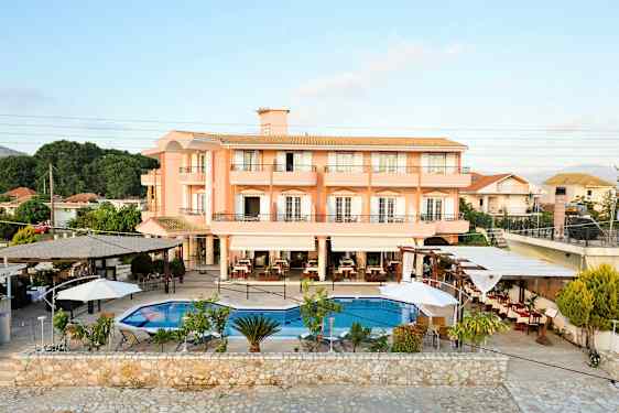 Et hotell med ferskenfargede fasader og et utendørs basseng med omkringliggende sitteplasser. (AI-generert tekst)