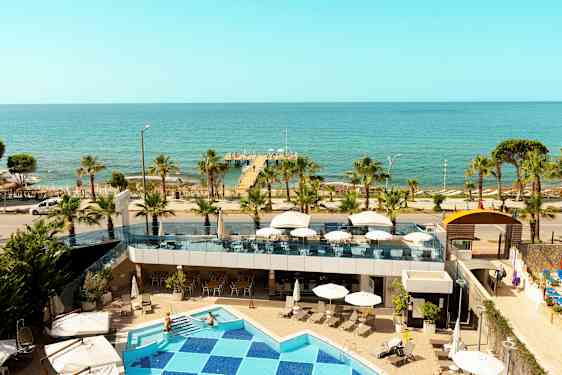 Utsikt fra hotellet mot havet med basseng, terrasse og brygge. (AI-generert tekst)