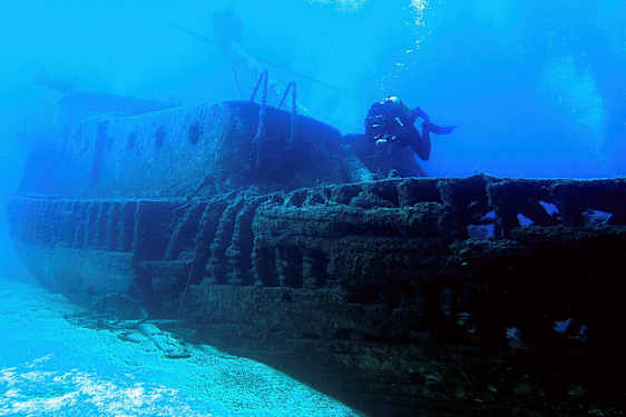 Et undervannsfotografi av et sunket skip med en dykker som svømmer ved siden av. (AI-generert tekst)