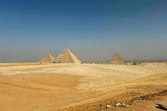 Bildet viser de store pyramidene i Giza omgitt av ørkenlandskap. (AI-generert tekst)