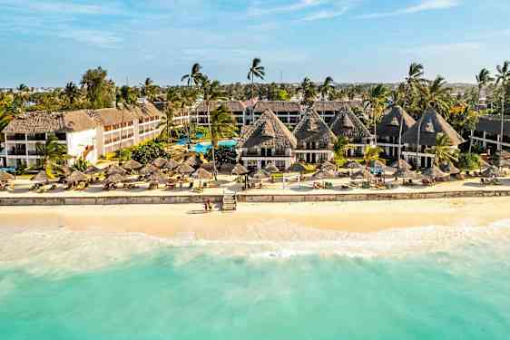 Hotell ved en sandstrand med palmer og parasoller. (AI-generert tekst)