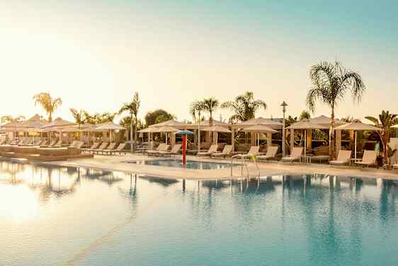 Utendørsbasseng omgitt av solsenger og parasoller. (AI-generert tekst)