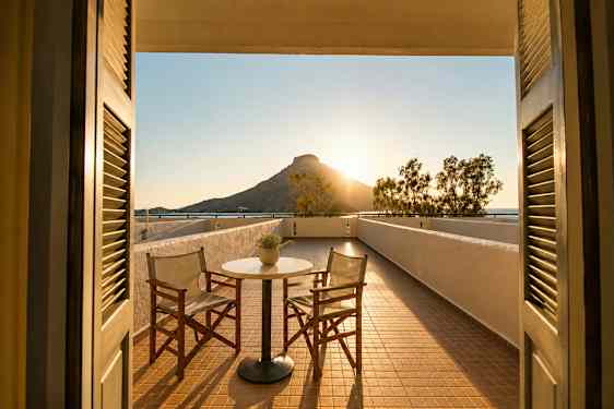 En terrasse med to stoler og et bord, med utsikt over et fjell ved solnedgang. (AI-generert tekst)