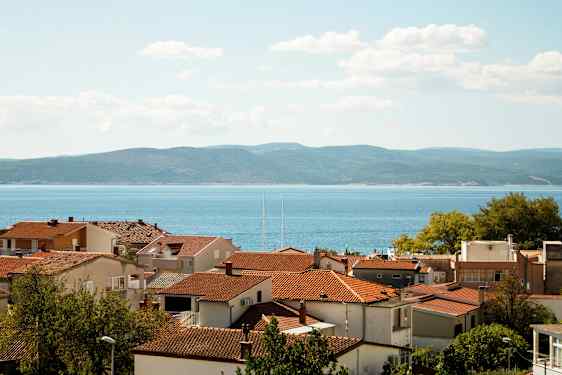 Røde hustak med sjøen og åser i bakgrunnen. (AI-generert tekst)