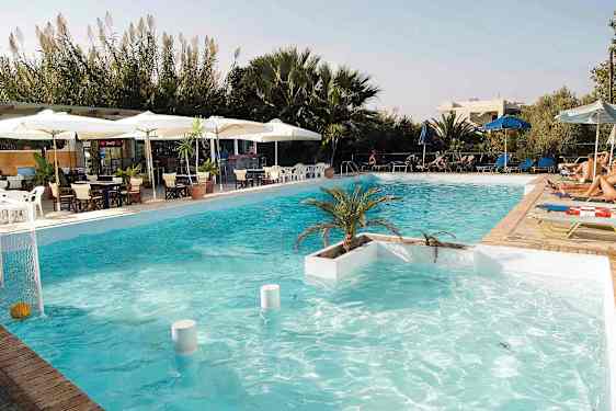 Et svømmebasseng med solsenger, parasoller og et serveringsområde i bakgrunnen. (AI-generert tekst)