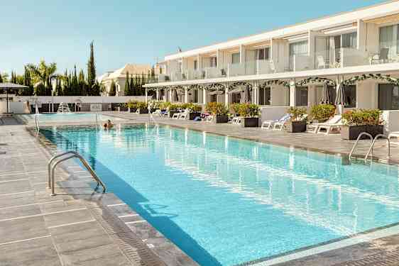 Et hotellbasseng med solsenger og parasoller på siden. (AI-generert tekst)