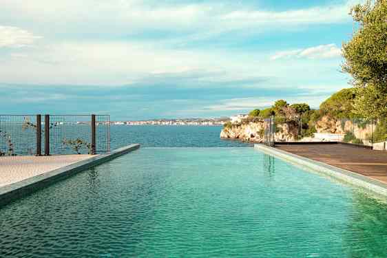 Et infinitybasseng med utsikt over havet og klipper i bakgrunnen. (AI-generert tekst)