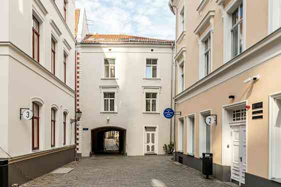 En smal gate omgitt av lyse bygninger med vinduer og dører. (AI-generert tekst)