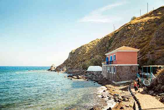 Hus ved sjøen ved siden av en klippe. (AI-generert tekst)