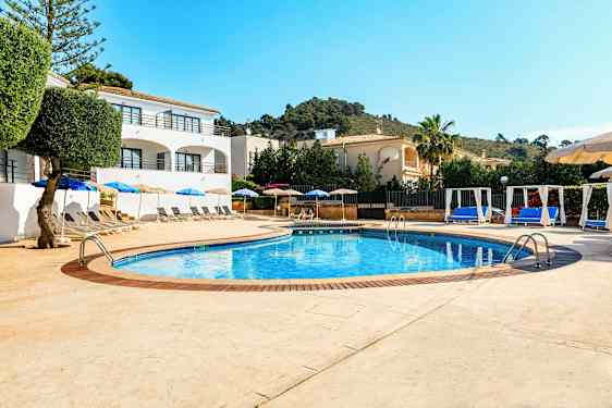 Bassengområde med solsenger og parasoller samt omkringliggende bygninger. (AI-generert tekst)