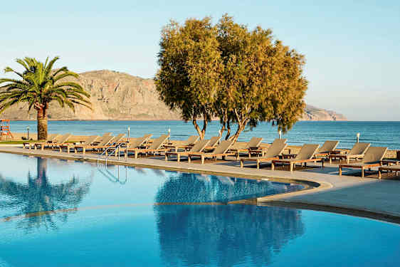 Et basseng med solsenger og utsikt over havet og fjellene. (AI-generert tekst)