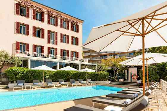 Hotellbygning med basseng og solsenger foran. (AI-generert tekst)