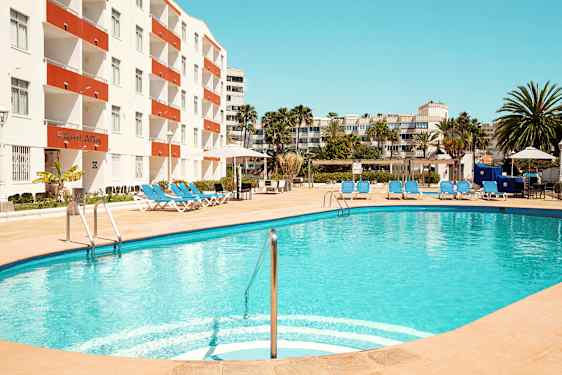 Et utendørs svømmebasseng med solsenger ved et hotell. (AI-generert tekst)