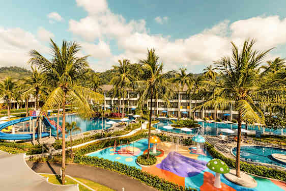 Bilde av et hotellområde med bassenger, vannsklie og fargerike lekeområder omgitt av palmer. (AI-generert tekst)