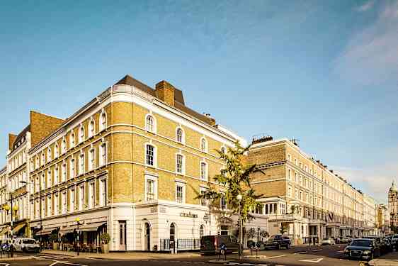 En gate med en rekke klassiske bygninger og parkerte biler. (AI-generert tekst)