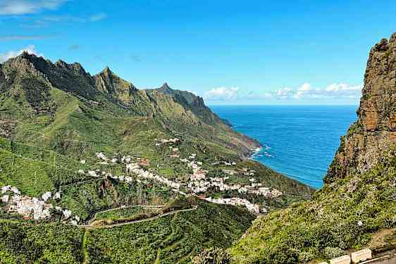 Utsikt over en fjellandsby ved havet, omgitt av grøntområder. (AI-generert tekst)