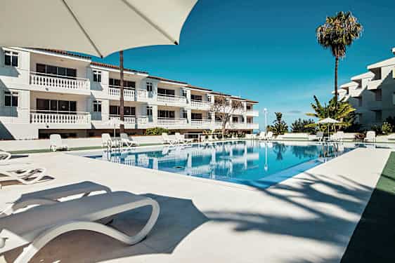 Et basseng ved et hotell med solsenger og parasoller. (AI-generert tekst)