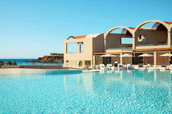 Et svømmebasseng ved et hotell med havet i bakgrunnen. (AI-generert tekst)