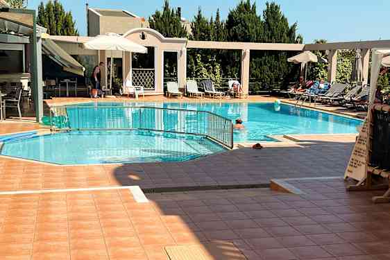 Utendørs svømmebasseng med solsenger, parasoller og mennesker som koser seg i området. (AI-generert tekst)