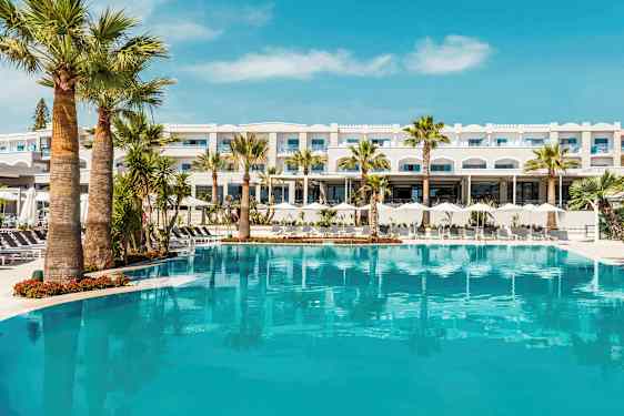 Hotellbygning bak et stort basseng med palmer. (AI-generert tekst)