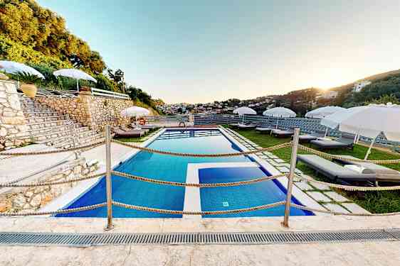 Utendørs basseng med solsenger og parasoller på en terrasse. (AI-generert tekst)