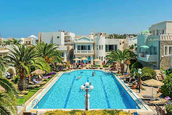 Et basseng omgitt av palmer, solsenger og bygninger under en klar blå himmel. (AI-generert tekst)