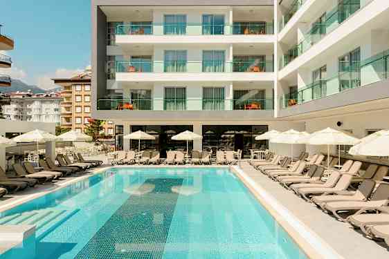 Bassengområde med solsenger og parasoller foran et hotell. (AI-generert tekst)