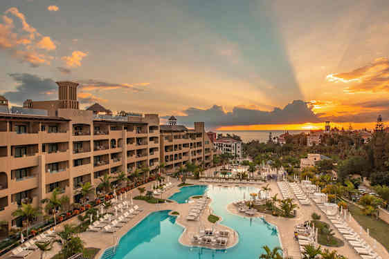 Utsikt over et hotell med bassengområde ved solnedgang. (AI-generert tekst)