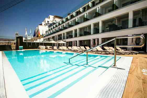 Utendørs basseng ved hotell med solsenger og glassbalkonger. (AI-generert tekst)