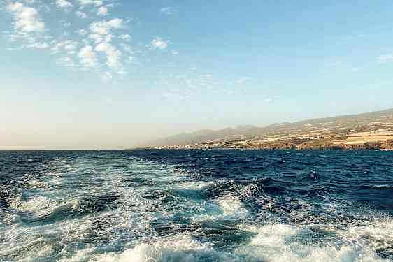 Havslandskap med bølger og kystlinje i bakgrunnen. (AI-generert tekst)