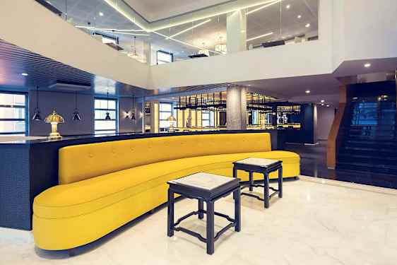 Et stilfullt innredet rom med en gul sofa, små bord og moderne belysning. (AI-generert tekst)