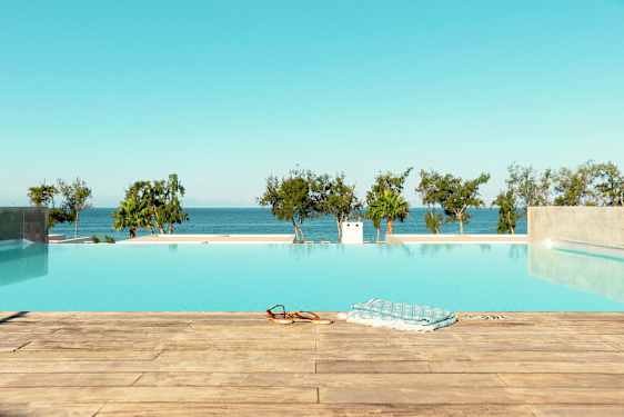 Bilde av et evighetsbasseng med utsikt over havet og trær i bakgrunnen. (AI-generert tekst)