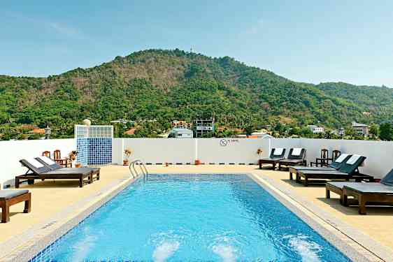 Utendørsbasseng med solsenger og fjell i bakgrunnen. (AI-generert tekst)