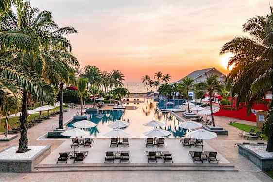 Et basseng med solsenger og parasoller ved solnedgang. (AI-generert tekst)